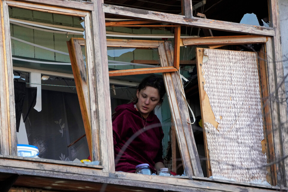 En kvinna står vid ett trasigt fönster i sin lägenhet efter en rysk bombning i Kiev i måndags.