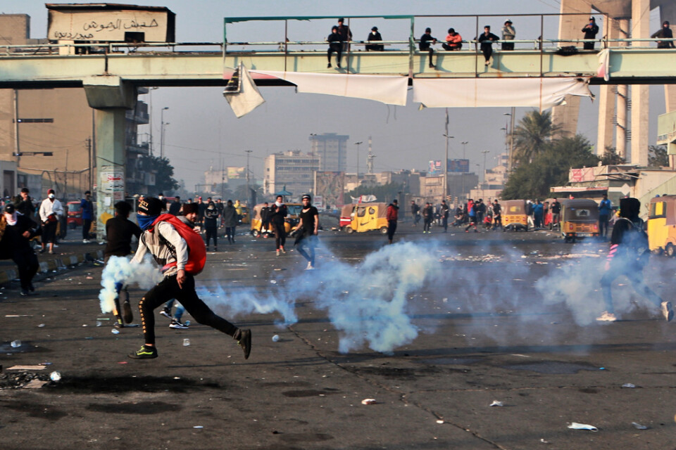 En demonstrant springer med en tårgaskanister i handen i Iraks huvudstad Bagdad på måndagen.