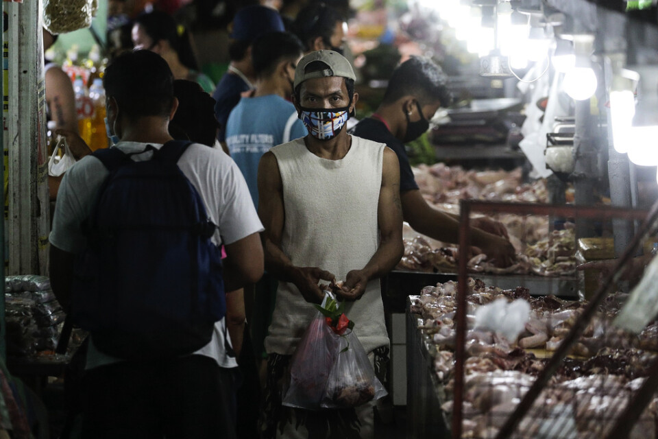 En man bär ansiktsmask på marknaden. Megastäder som filippinska Manila, där människor bor tätt och fattigdomen är utbredd, är en tacksam grogrund för smittspridning.
