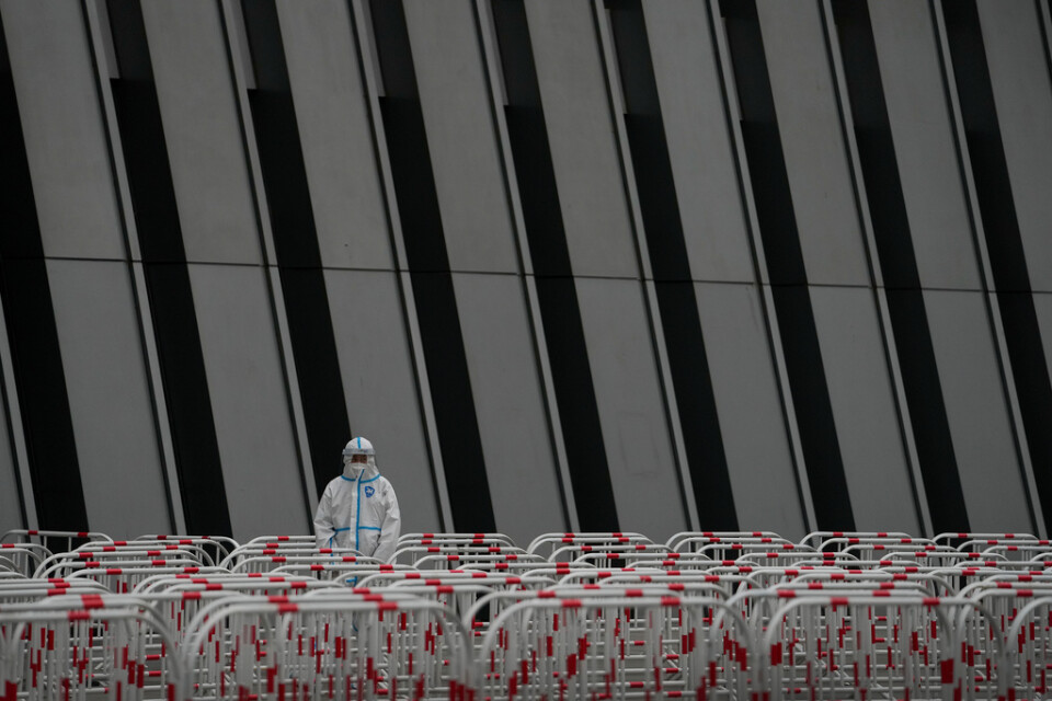 En skyddsdräktsklädd person håller koll på staket och avspärrningar vid en teststation i Peking, i söndags.