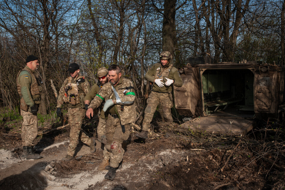 En skadad soldat har evakuerats från fronten i Bachmut i ett pansarfordon och leds iväg av sina kamrater. Bilden togs i måndags.