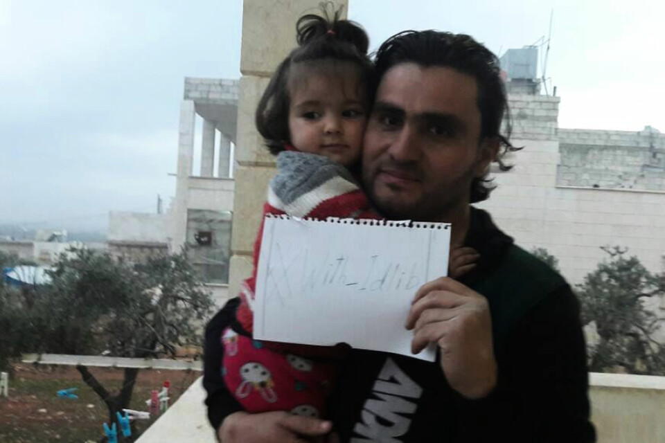 Den syriske läraren och aktivisten Abdulkafi Alhamdo tillsammans med dottern Lamar 2018. I handen håller han en lapp som uppmanar till sympati med Idlib. Arkivbild.