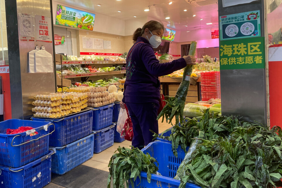 En kvinna i Kanton-provinsen handlar mat under torsdagen sedan en affär öppnat efter de lättade restriktionerna.