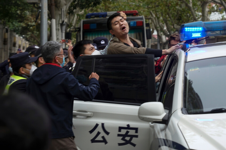 En man som har demonstrerat tvingas in i en polisbil i Shanghai i söndags.