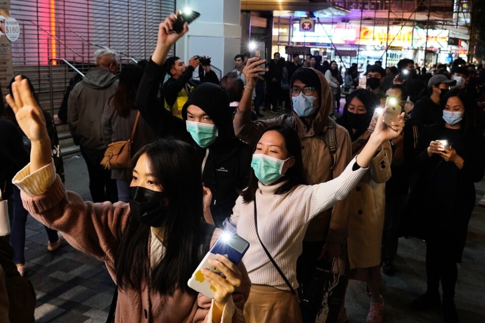 Demonstranter i Hongkong som bildat en mänsklig kedja håller upp sina telefoner med påslagna ficklampor under protester på nyårskvällen.
