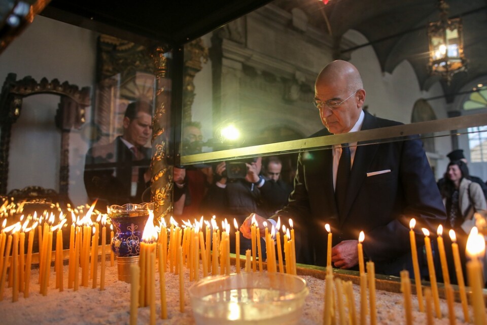 Greklands utrikesminister Nikos Dendias tänder ett ljus för offren under en minnesgudstjänst i Istanbul.