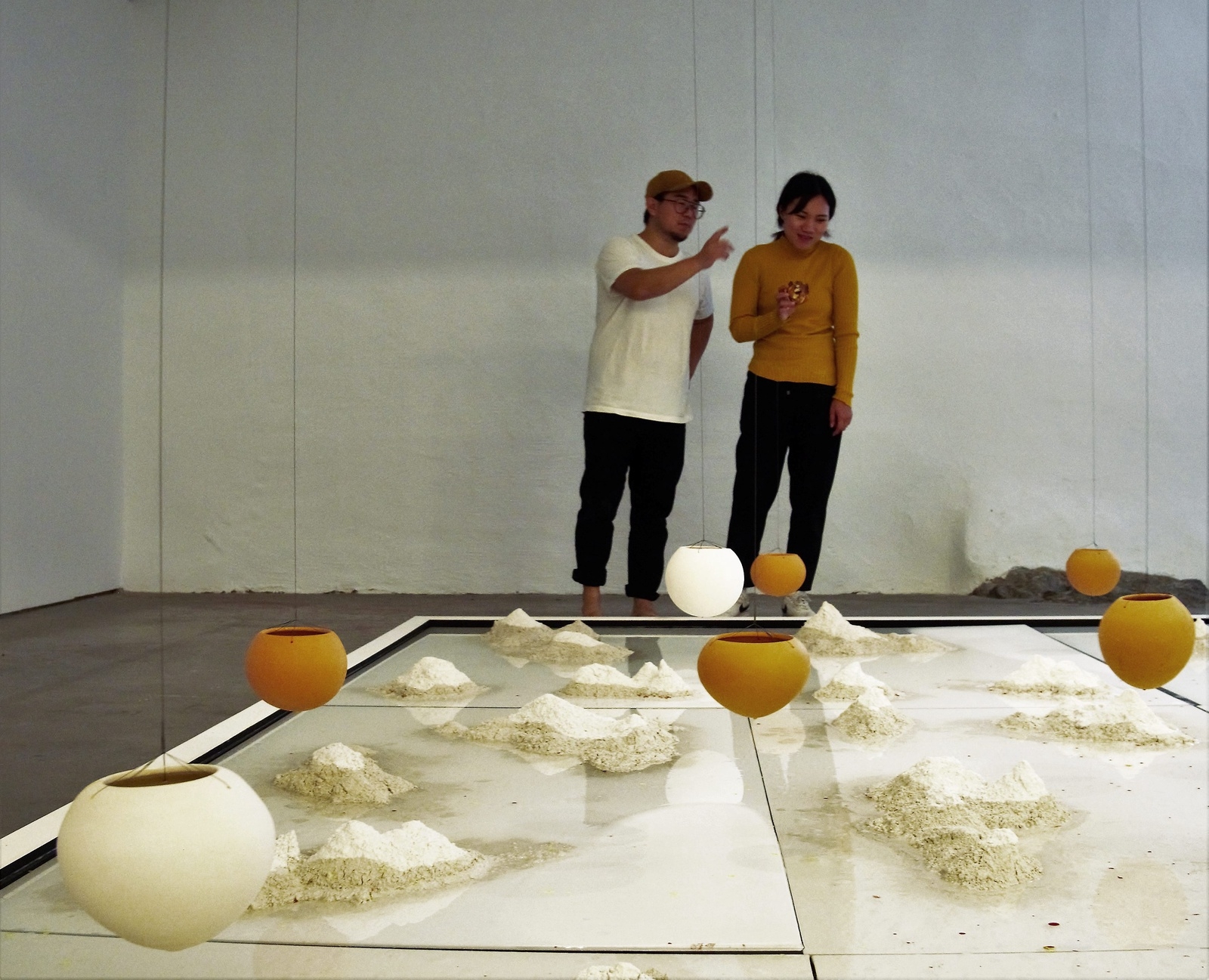 Konstnären Kyung-Jin Cho, i gult, pratar med maken Young Ill Kim medan de begrundar hennes konstinstallation. Foto: Teodor Dimblad