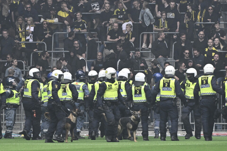 Poliser med hundar på plan framför AIK:s supportrar under söndagens fotbollsmatch i allsvenskan mellan Djurgården och AIK på Tele2 arena.