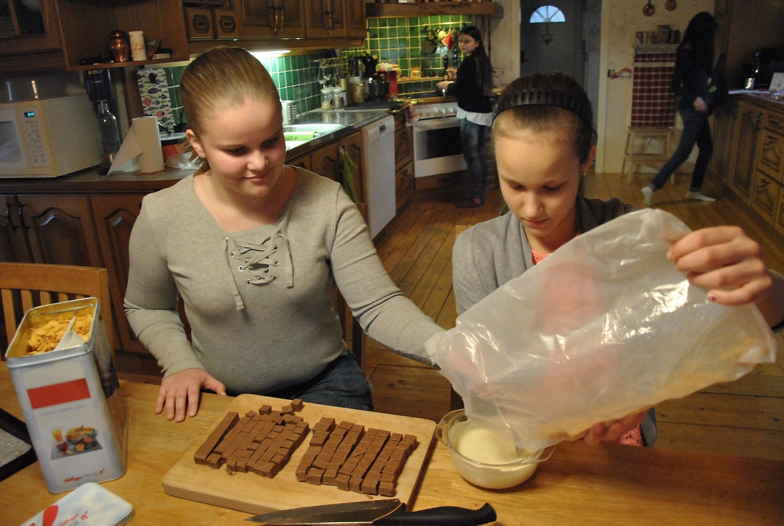 Krossade cornflakes ska blandas ner i den smälta, vita chokladen. Ida och Julia visar. 
Foto: Marie Strömberg Andersson