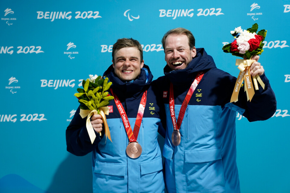 Zebastian Modin och hans ledsagare Emil Jönsson Haag vid medaljceremonin efter bronset i skidsprinten.
