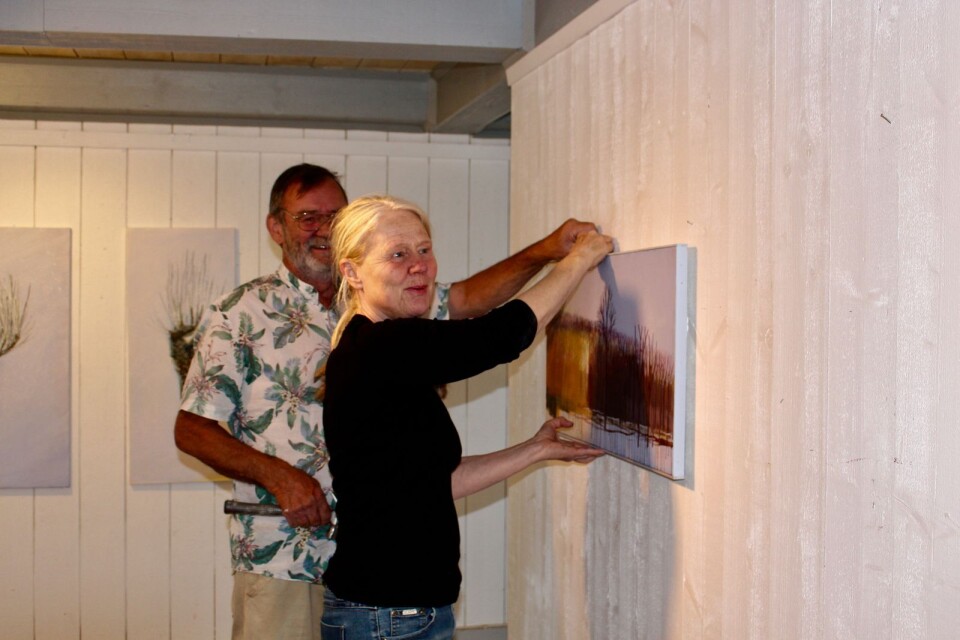 Elisabeth Lindstedt får hjälp av hjälpredan, Svante Höglund, med att hänga upp tavlorna.