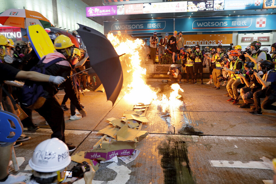 Demonstranter tänder eld på pappkartonger för att hindra polisen att göra framstötningar.
