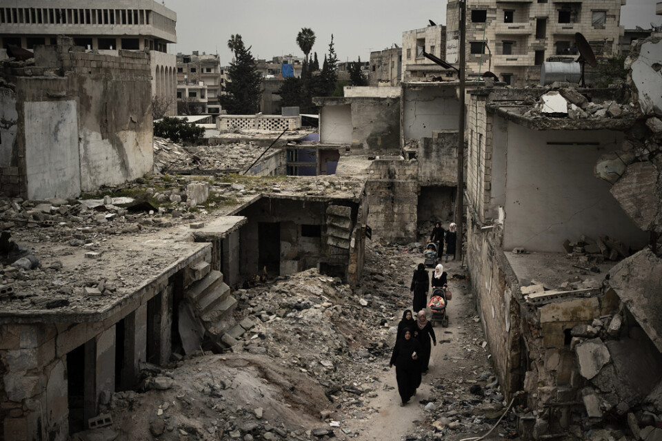 Kvinnor passerar ett sönderbombat bostadsområde i Idlib i nordvästra Syrien. Bilden togs i mars i fjol.