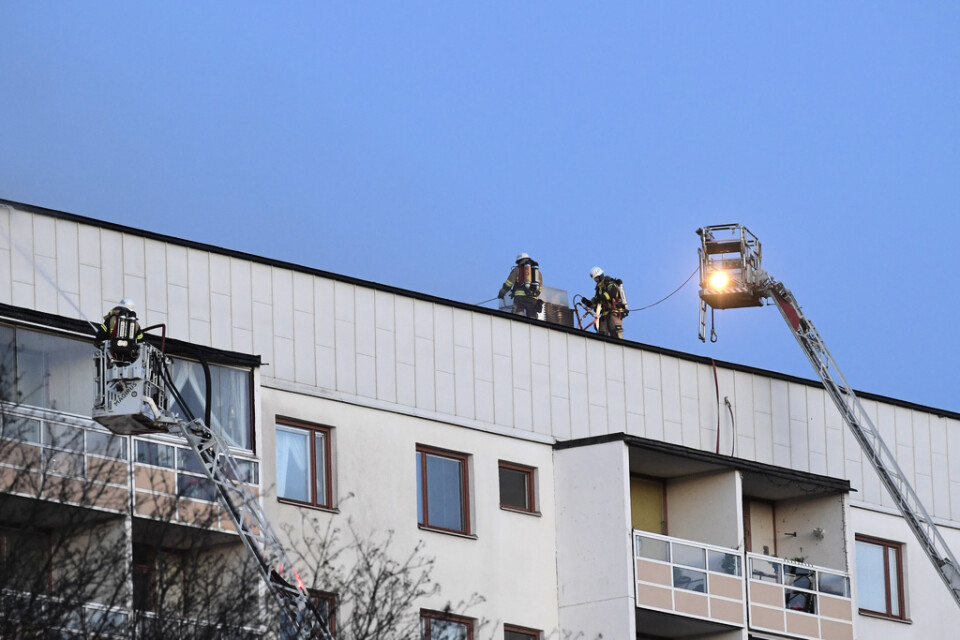Räddningstjänsten arbetar på taket till ett åttavåningshus som började brinna i Hagsätra i södra Stockholm på söndagseftermiddagen.
