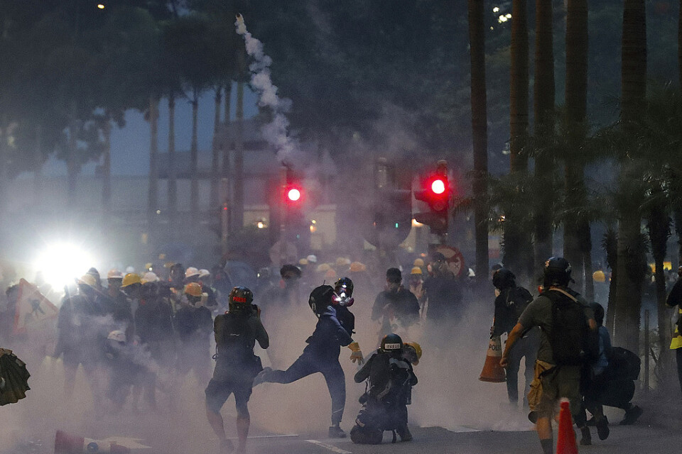 En demonstrant kastar tårgas avfyrad av polis under demonstrationerna på söndagen, då vilda protester återigen tog över gatorna i Hongkong.