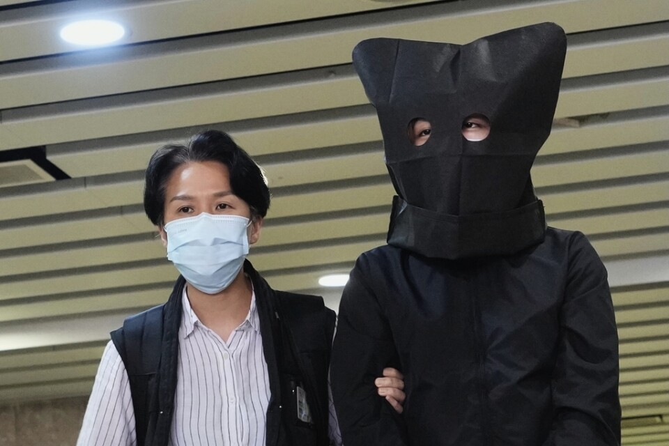En misstänkt eskorteras av polis för att leta efter bevis på ett kontor i Hongkong den 22 juli. Polisen grep fem personer som misstänks ha förberett att sprida "uppviglande" litteratur riktade mot barn – ett av de senaste tillslagen mot dissidenter i Hongkong.