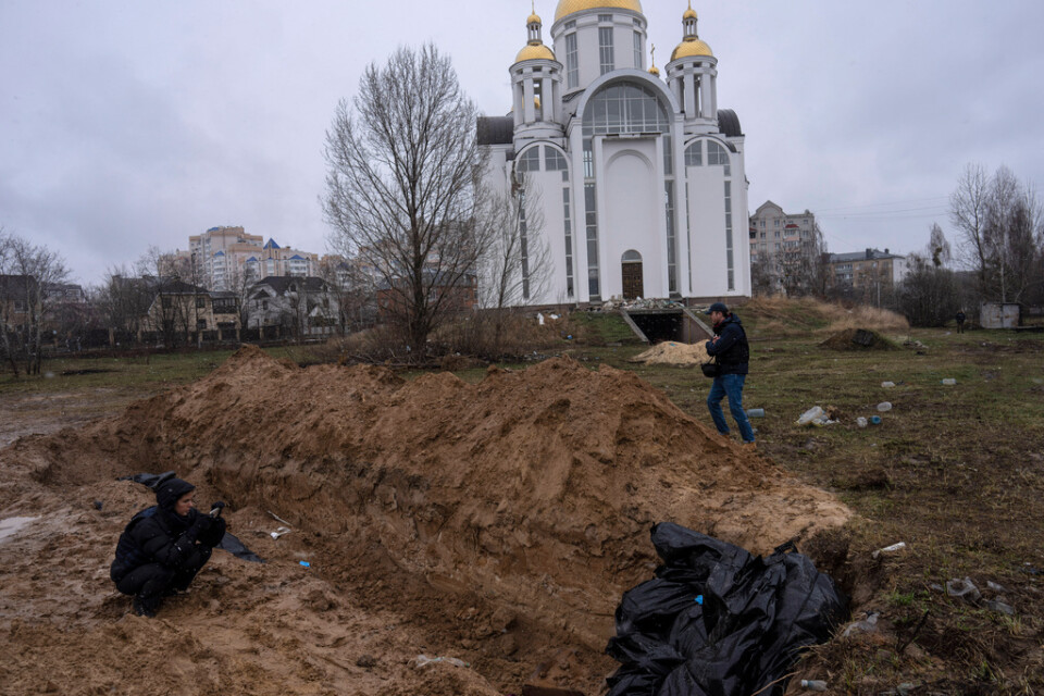 Journalister dokumenterar en massgrav vid kyrkan i den ukrainska staden Butja söndagen den 3 april.