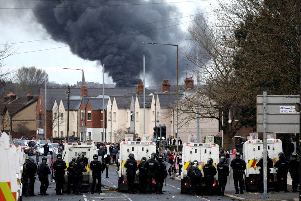 Kravallpolis spärrar en väg i Belfast för att hålla isär grupper som drabbade samman, den 7 april förra året. Röken kommer från en kapad buss som stuckits i brand.
