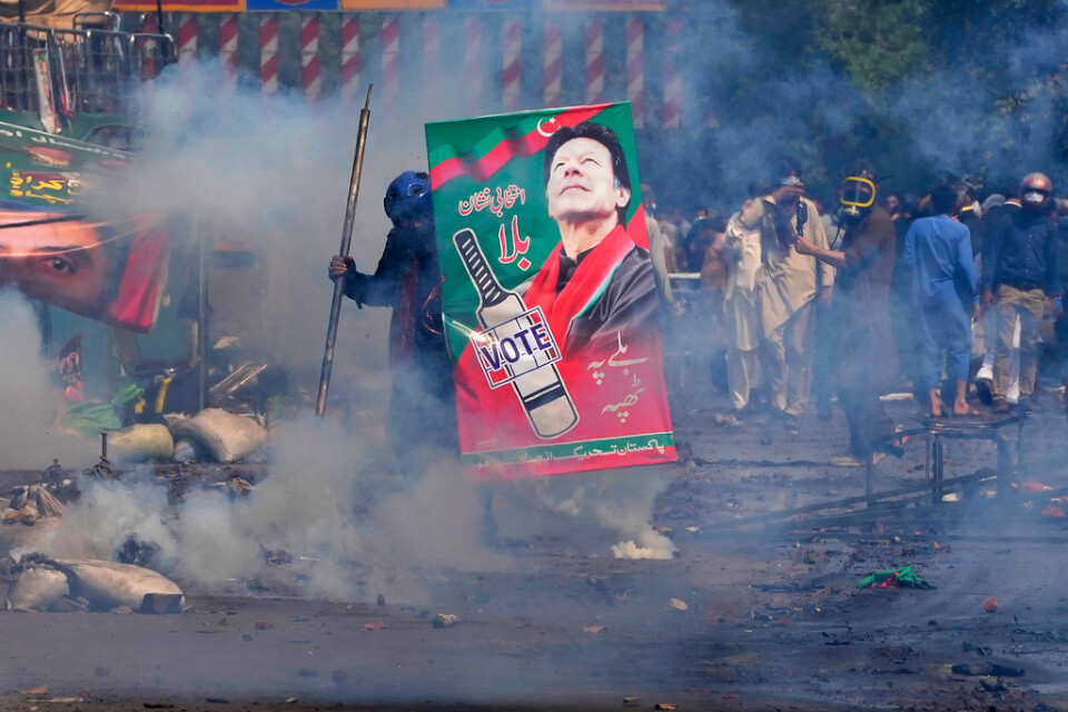 En anhängare till Imran Khan tar skydd bakom ett plakat med dennes bild tidigt på onsdagsmorgonen.