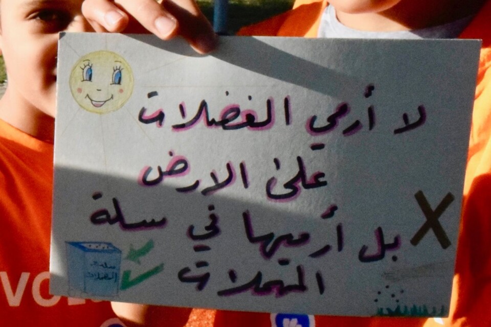 Barnen har skyltar på svenska och arabiska med budskap om att hålla rent.