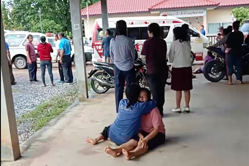 En stillbild från en video visar hur en uppriven kvinna tröstas utanför förskolan i norra Thailand.