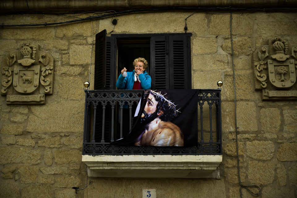 En kvinna ringer i en klocka från sin balkong i San Vicente de La Sonsierra i norra Spanien. Påskfirandet får ske på andra sätt när offentliga samlingar ställs in.