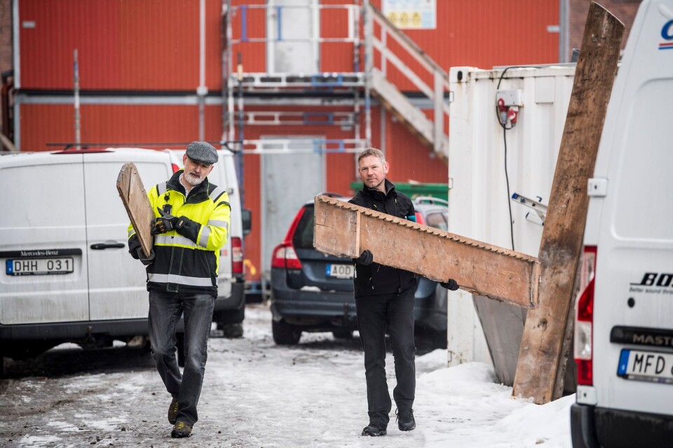 Byggnadsarkivarie Ivar Wenster och museichef Marcus Sandekjer bär ut plankorna från byggarbetsplatsen vid Fredrikskyrkan.
