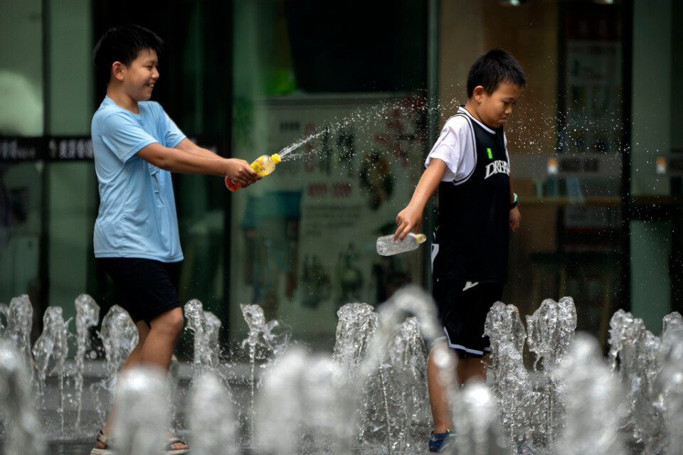 Pojkar svalkade sig vid en fontän i Peking i lördags, när temperaturen steg till runt 40 grader Celsius.