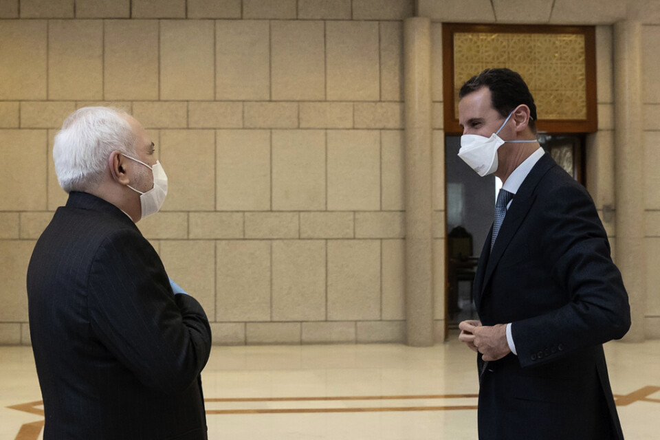 Syriens president Bashar al-Assad, i munskydd till höger, tillsammans med Irans utrikesminister Javad Zarif.
