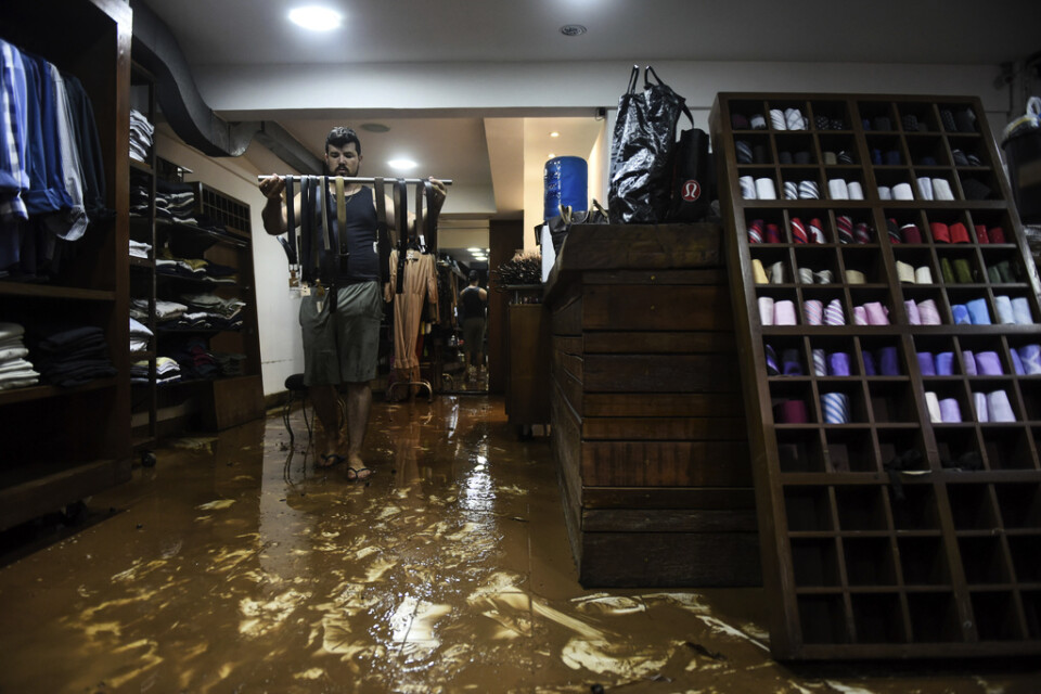 En anställd försöker rädda varor i en översvämmad klädbutik i staden Belo Horizonte i Brasilien.