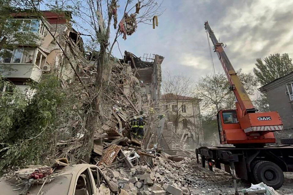 Räddningsarbetare vid en byggnad som raserats i vad Ukraina hävdar är en rysk attack i staden Zaporizjzja.