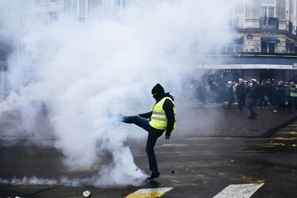 En demonstrant sparkar i väg en tårgaspatron i Paris.