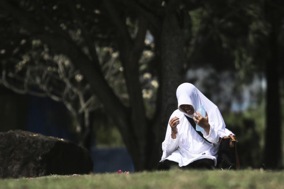 En kvinna ber vid en massgrav i Banda Aceh i Indonesien på torsdagen.