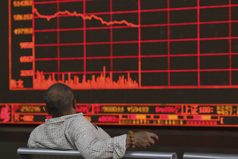 En kinesisk investerare betraktar Shanghais kompositindex som föll kraftigt under måndagen efter Trumps hot om höjda handelstullar mot Kina.