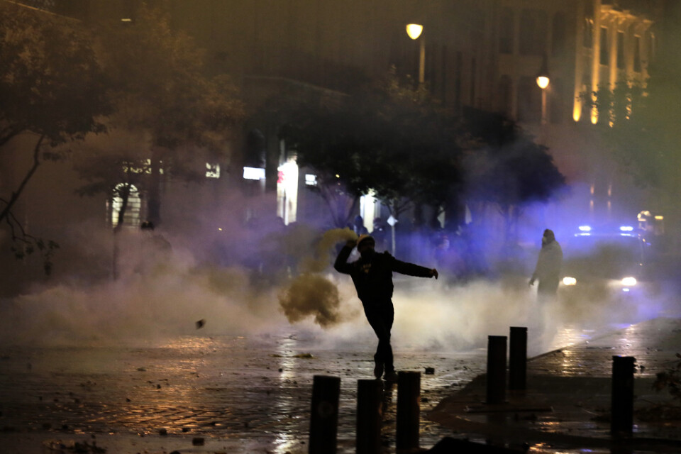 En demonstrant kastar tillbaka en tårgasbehållare mot kravallpoliser.
