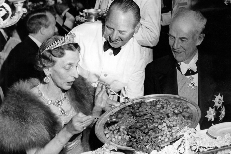 Kronprinsessan Louise tar för sig av den stekta kycklingen med selleri, majrovor, lök och bacon medan riksmarskalk Birger Ekeberg ser på under Nobelbanketten 1947. Arkivbild.