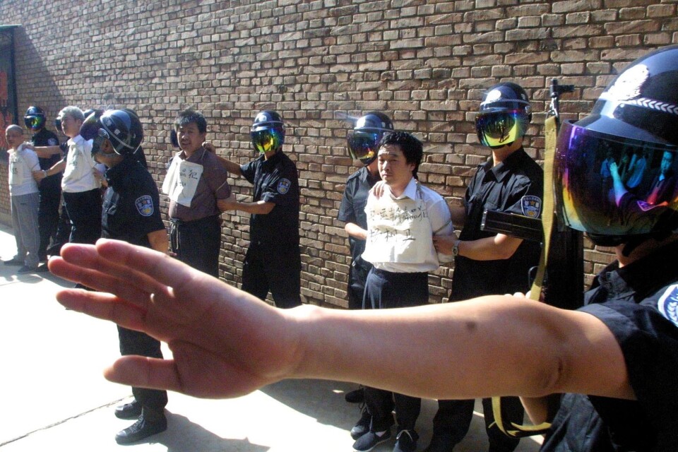 En polis håller journalister på avstånd när fyra knarksmugglare ställs upp för att avrättas i Xian i nordvästra Kina i juni 2004. Kina avrättar fler personer än något annat land. Arkivbild.