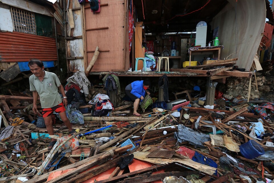 Boende försöker rädda föremål från sina förstörda hus i staden Lapu-Lapu efter kraftiga oväder i lördags.