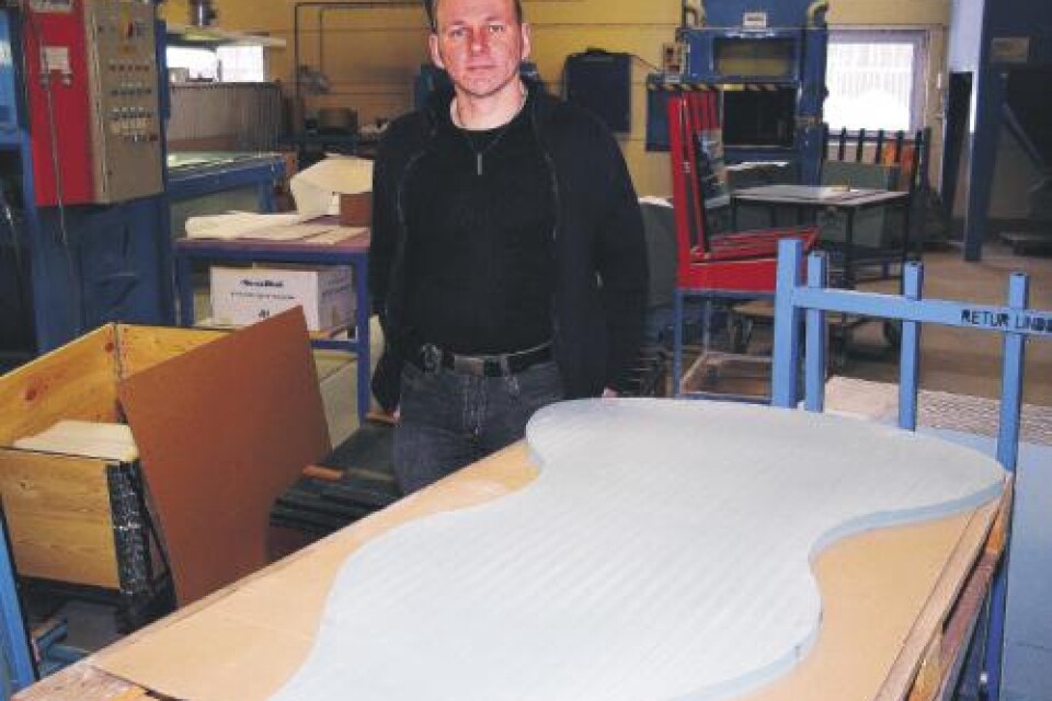 Vd Joakim Hultqvist med en glasskiva till bord som formgivaren Kjell Engman på Orrefors Kosta Boda designat.