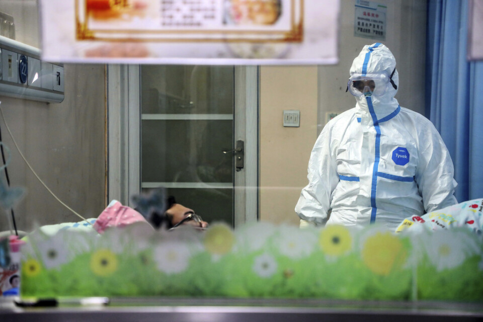 En läkare undersöker en patient i ett isoleringsrum på ett sjukhus i Wuhan.