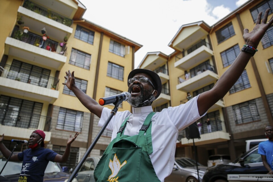 Paul Machira sjunger och predikar för boende i ett lägenhetsområde i den kenyanska huvudstaden Nairobi. Runt om honom sjunger och dansar barn på sina balkonger.