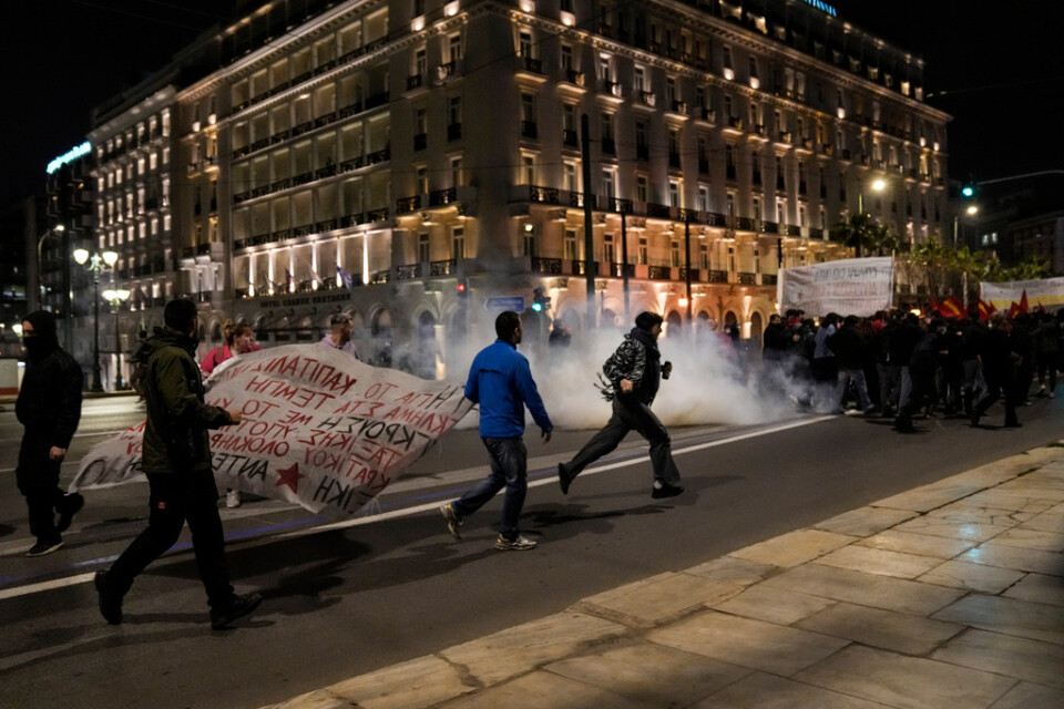 Demonstranter springer för att undvika tårgas från kravallpoliser framför parlamentet i Aten på onsdagskvällen.
