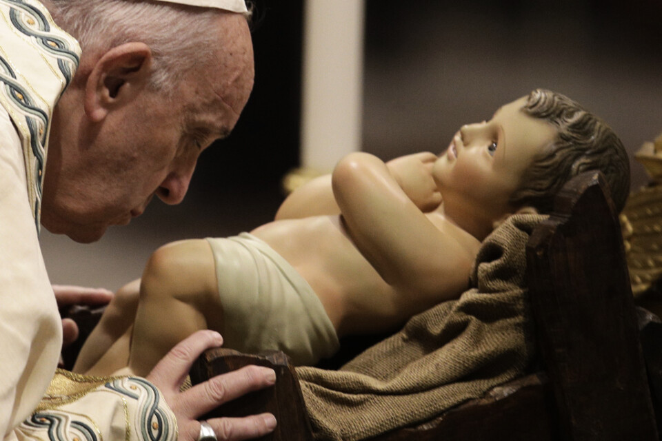 Påve Franciskus kysser en staty av Jesusbarnet i Peterskyrkan i Vatikanen.