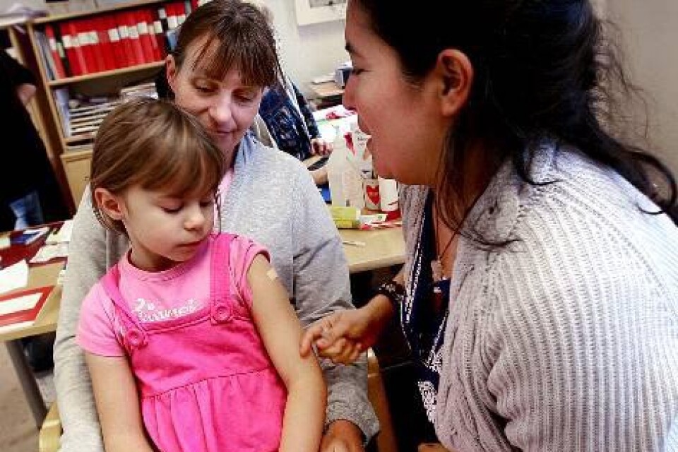 Alexandra Papalexi, 6 år, får här sitta i mammas knä medan skolsköterskan Ada Barahona ger henne ett vaccin mot svininfluensan.