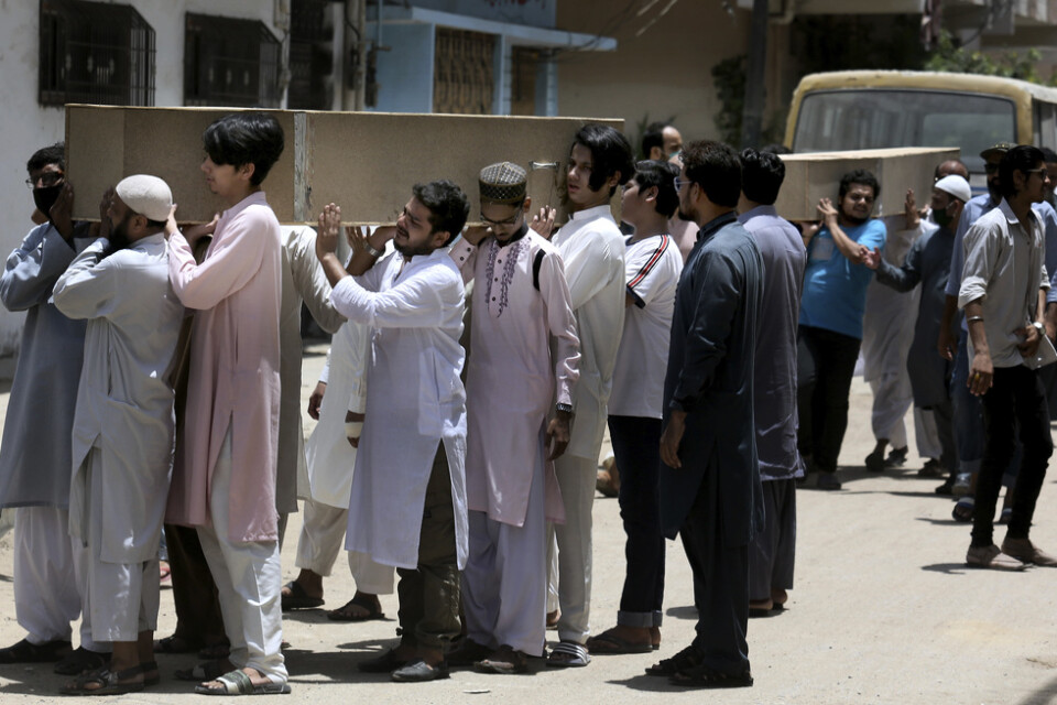 Människor bär kistor med offer från flygkraschen i Karachi.