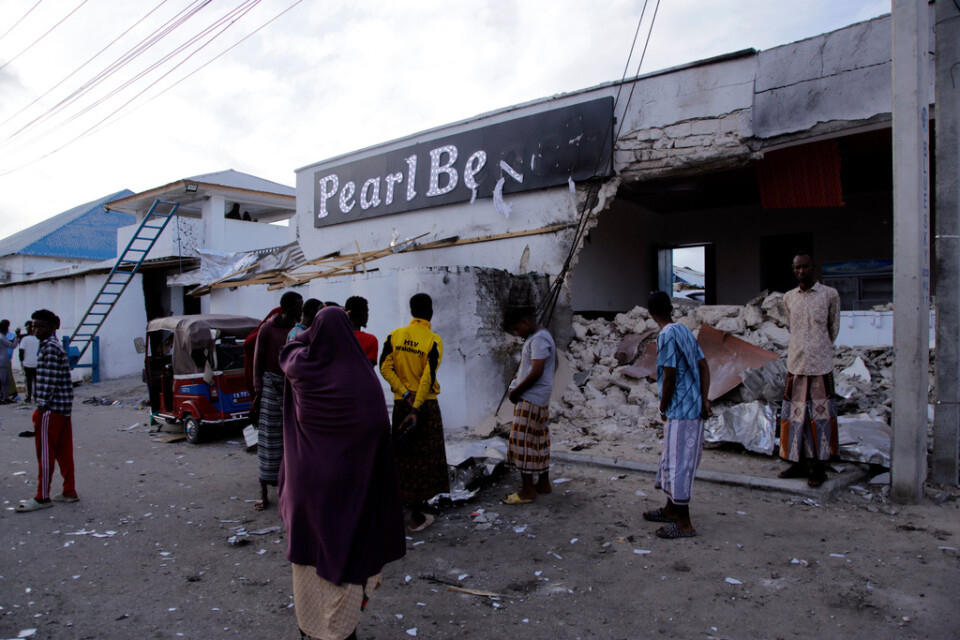 Människor betraktar förstörelsen utanför hotellet Pearl Beach i Somalias huvudstad Mogadishu, som attackerades av terrorgruppen al-Shabab på fredagen.