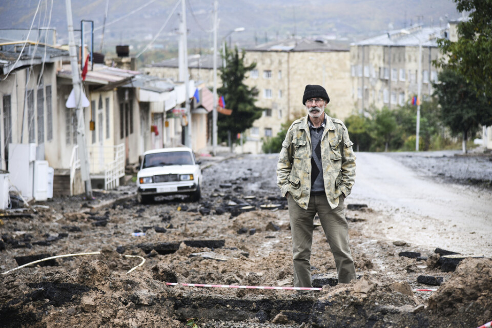 En man står och begrundar en asfaltsväg som pulvriserats i ett bombanfall, i Stepanakert. Bilden har skickats ut av myndigheterna i Nagorno-Karabach.
