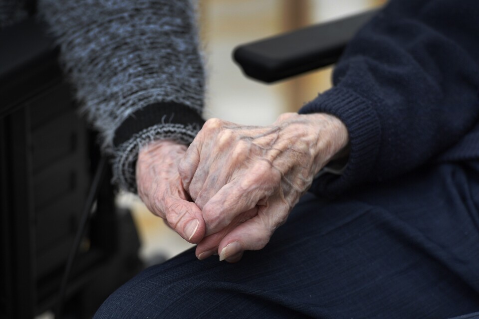 Trygghet. Två personer håller varandra i handen på ett äldreboende.
