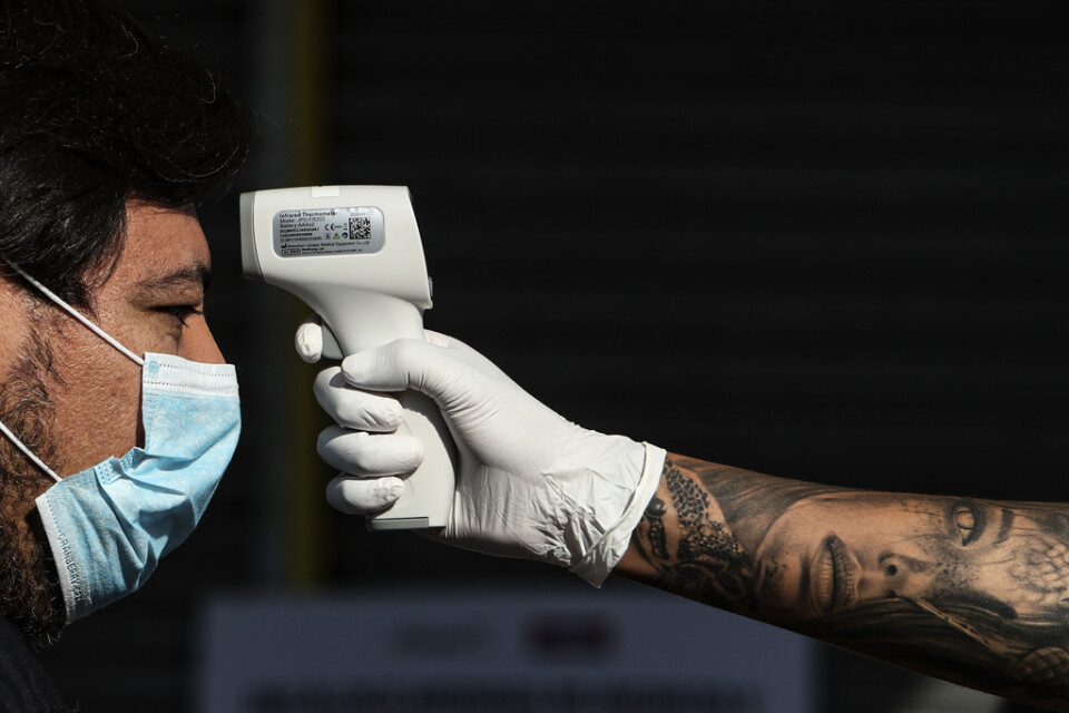Sjukvårdsarbetare tar temperaturen på en man i Chiles huvudstad Santiago på torsdagen.