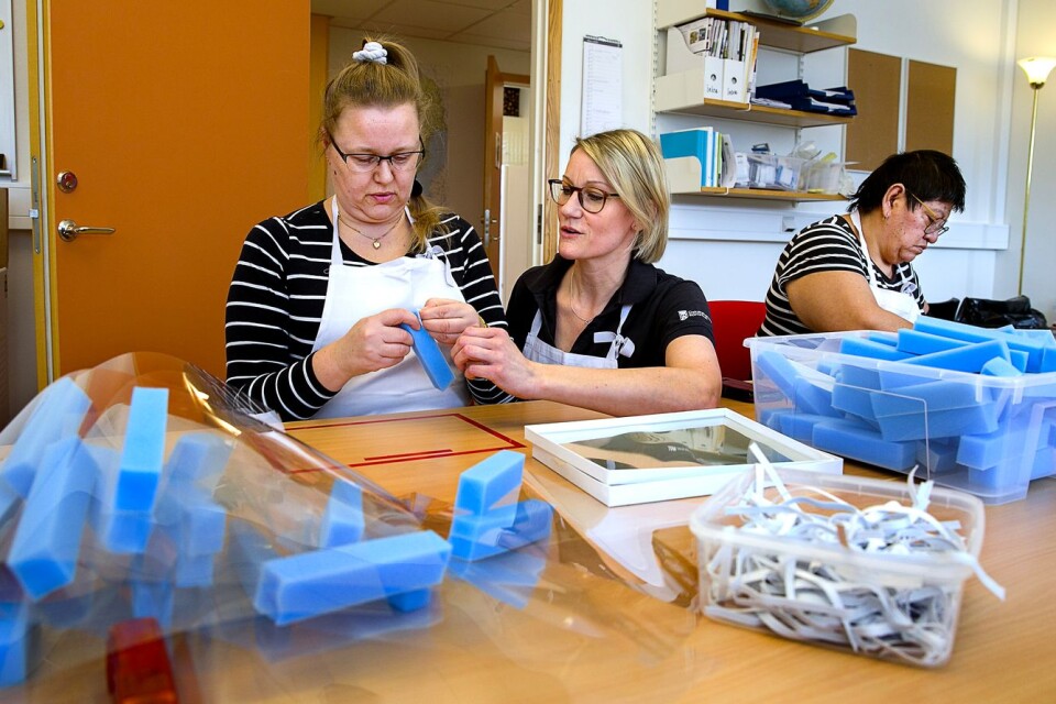 Kristina Svensson får hjälp av Emma Blomqvist. Elsa Eriksson arbetar också med att sätta ihop visir.